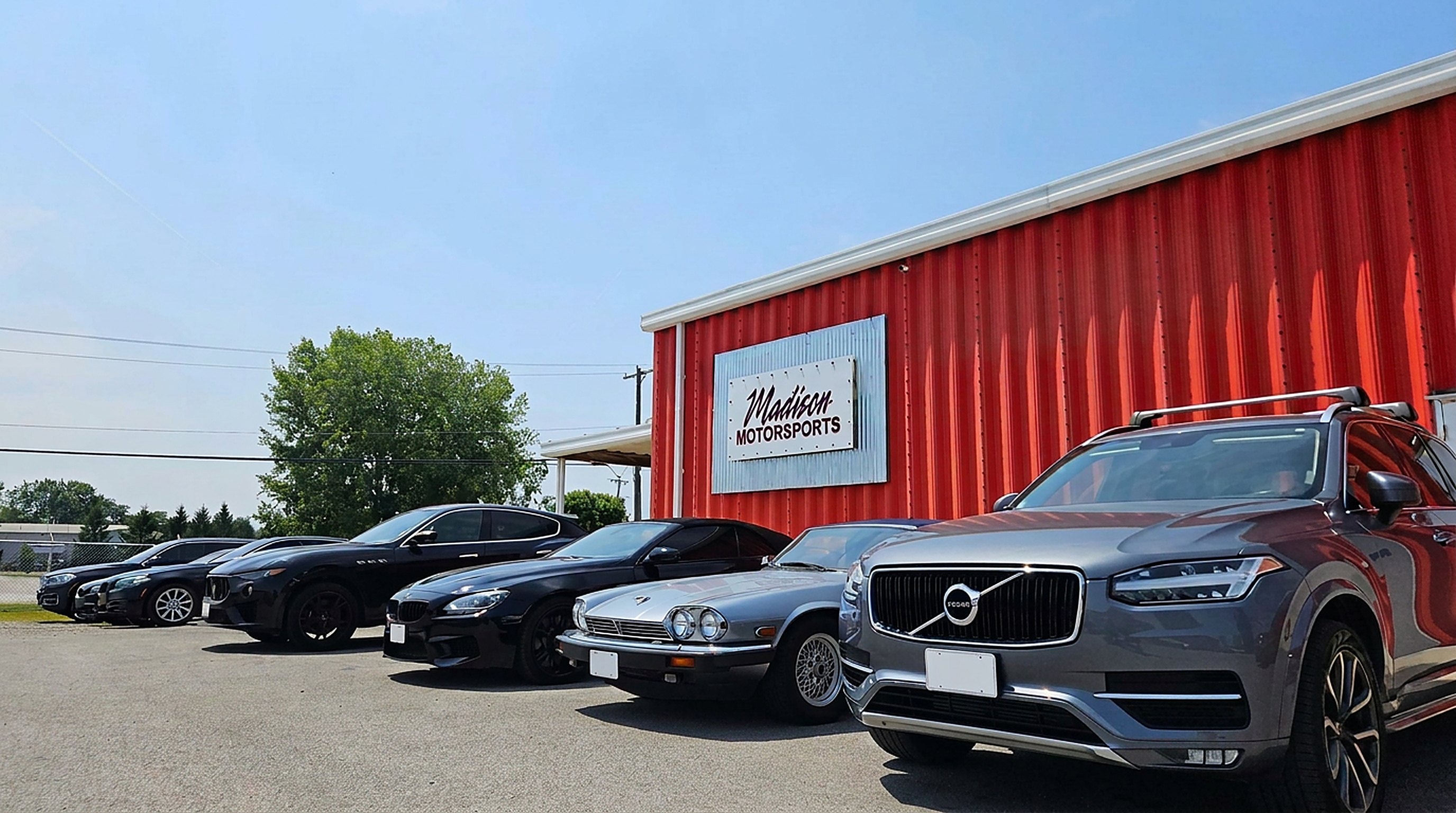 Lineup of European cars along the red Madison Motorsports building
